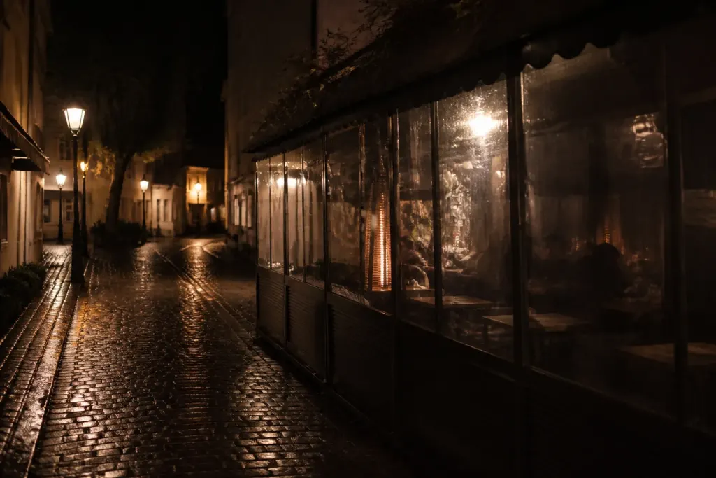 Rue pavee de nuit avec lampadaires et terrasse fermee